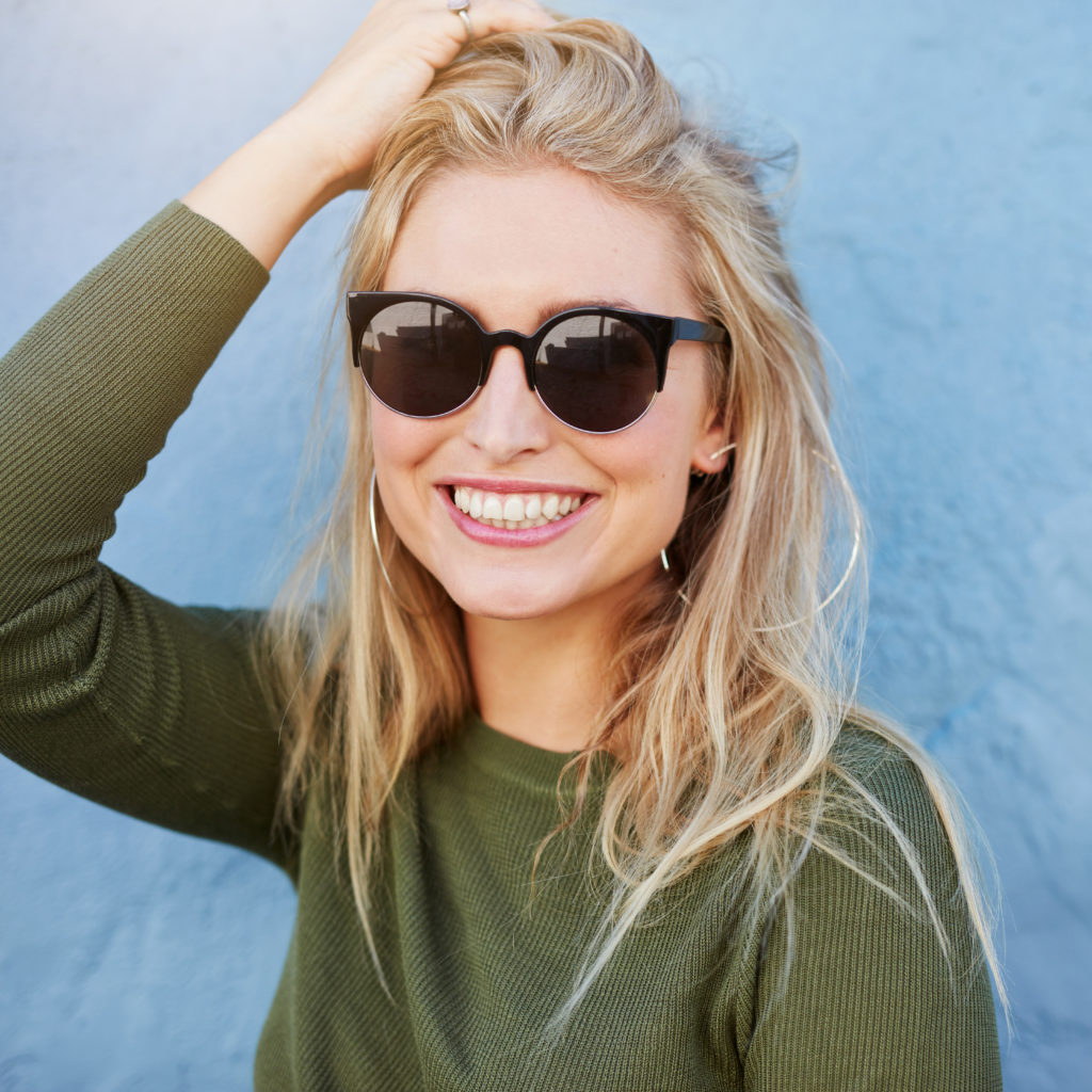 femme heureuse avec des lunettes de soleil qui se passe la main dans les cheveux